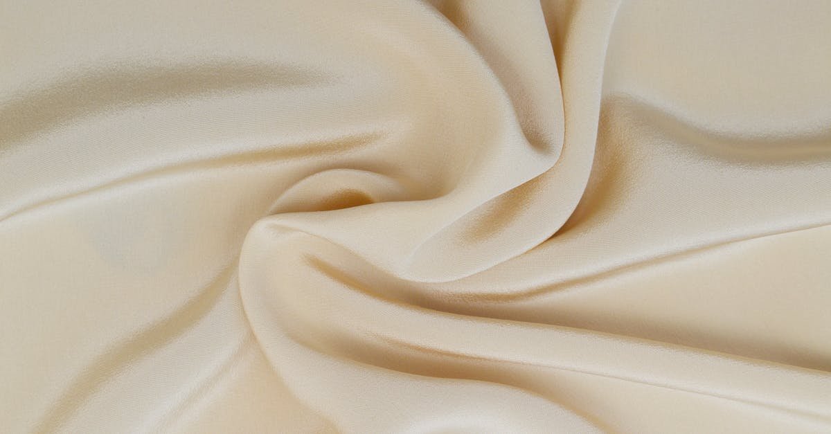 Close-up of beige silk fabric showcasing elegant texture and softness, ideal for textile designs.